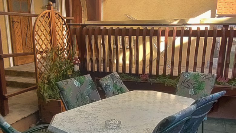 Kryt&aacute; terasa se stolem a židlemi.