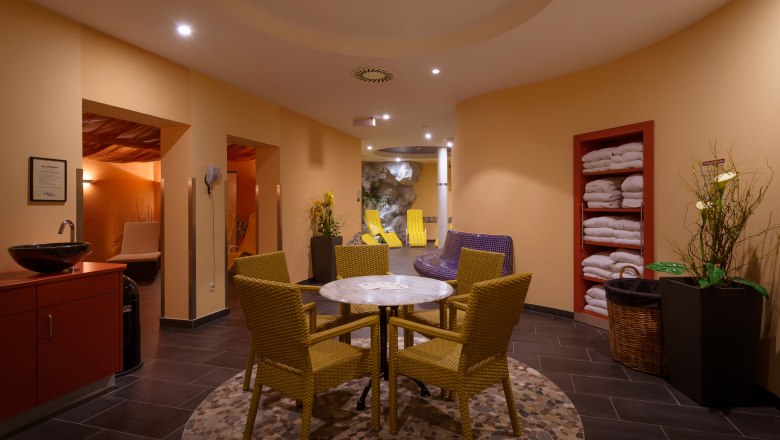 Wellnessbereich eines Hotels mit Tisch, Stühlen und Liegen.