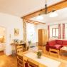 Gem&uuml;tliches Wohnzimmer mit Holzm&ouml;beln, rotem Sofa und offener K&uuml;che.