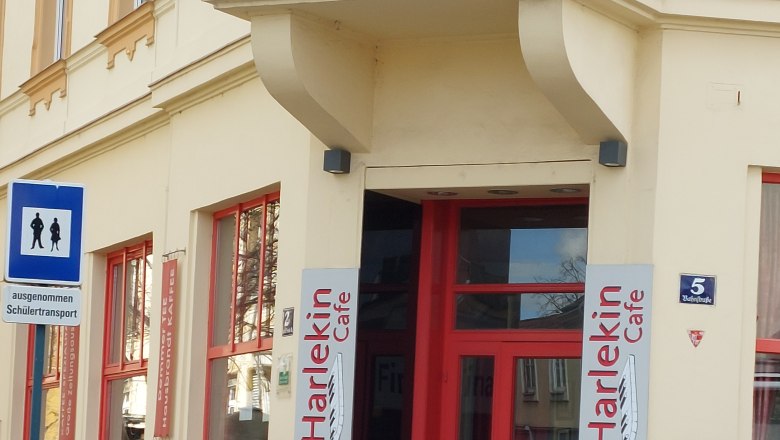 Eingang des Cafe Harlekin mit roter Tür und Eistüten-Dekoration.