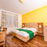Double bed in a room with a dark floor and yellow back wall