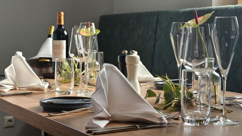 Elegant table setting with wine glasses, wine bottles and folded napkins.