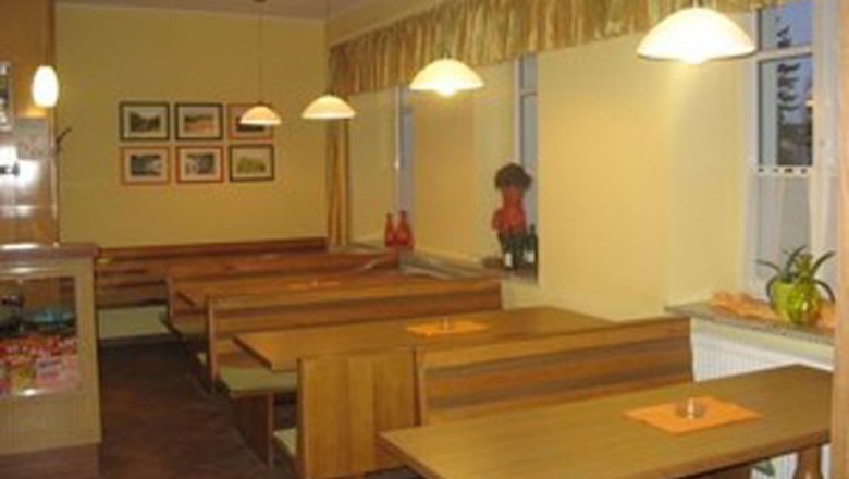 Innenansicht eines Restaurants mit Holztischen und Bänken.