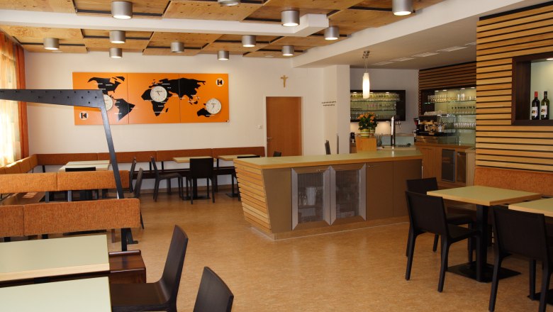 Innenansicht eines modernen Restaurants mit Holzelementen und Weltkarten-Dekor.