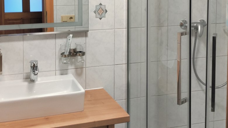 Modern&iacute; koupelna se sprchov&yacute;m koutem, umyvadlem a zrcadlem.