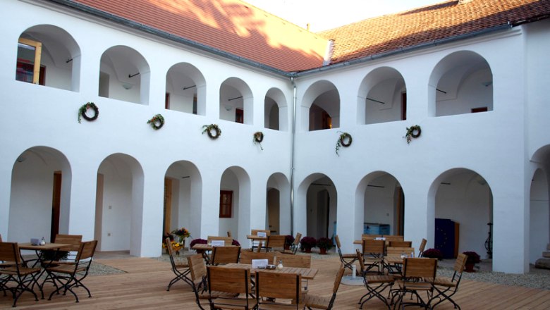 Innenhof des Eisenhuthauses mit Arkaden und Holzmöbeln.