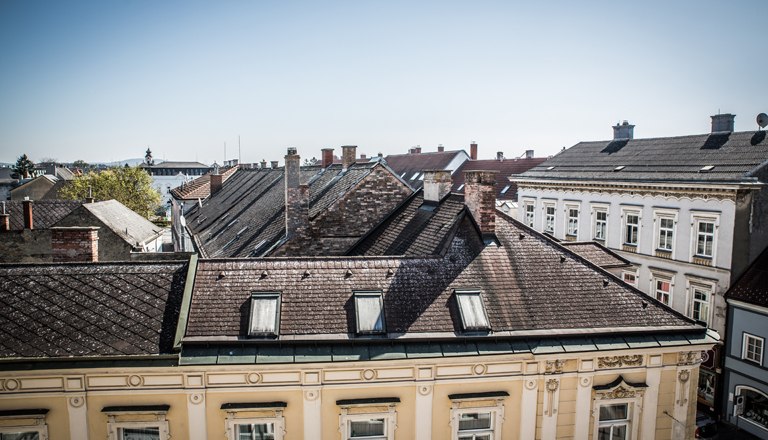 Ausblick auf Dächer der Nachbargebäude und blauem Himmel.