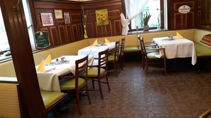 &Uacute;tuln&aacute; restaurace s dřevěn&yacute;mi stěnami, kryt&yacute;mi stoly a zelen&yacute;mi židlemi.