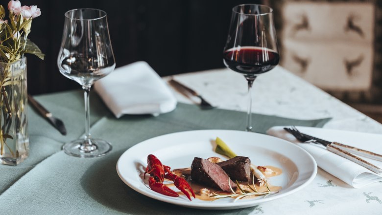Elegant dinner with meat, crayfish and red wine on a laid table.