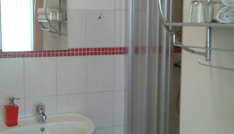 Ein Badezimmer mit Waschbecken, Spiegel, Dusche und Handtuchregal.