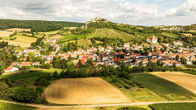 Luftaufnahme von Falkenstein mit Feldern, Weinbergen und einer Burg auf einem Hügel.