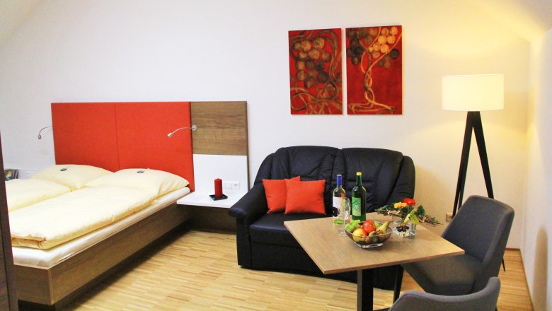 Gem&uuml;tliches Zimmer mit Doppelbett, Sofa, Tisch und Stehlampe.