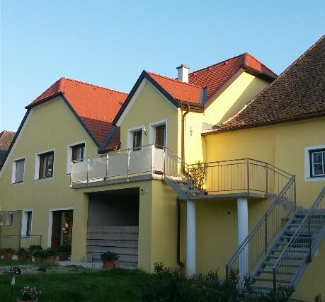 Žlut&aacute; budova s červen&yacute;mi střechami a vněj&scaron;&iacute;m schodi&scaron;těm.