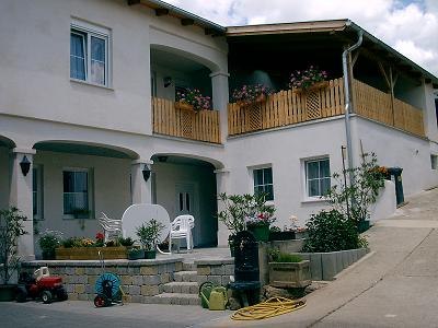 Dvoupodlažn&iacute; penzion s balkonem a květinami.