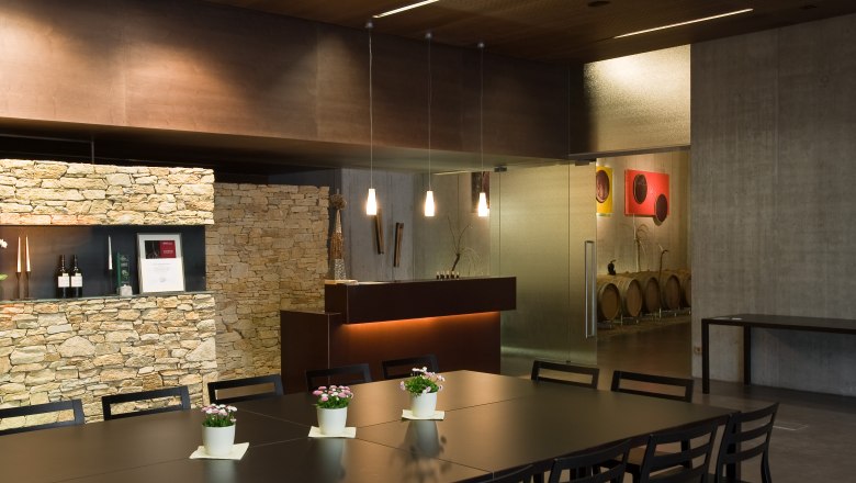 Modern tasting room with wooden table, chairs and stone wall.