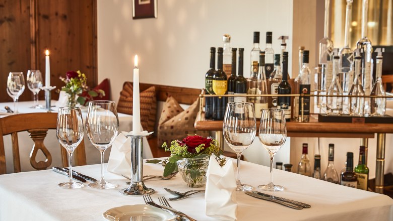 Eleganter Tisch in Hotel-Restaurant mit Weingläsern, Kerze und Blumen.