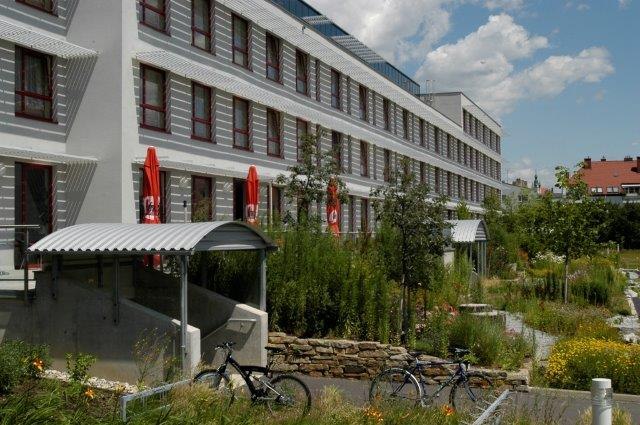 Kolping Campus Krems GmbH, © Kolping Campus Krems GmbH Moderní několikapatrová budova obklopená zelenou krajinou s jízdními koly v popředí.