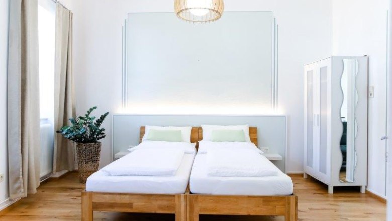 Modern guest room with two single beds, a closet and a plant.