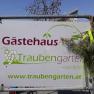 Schild mit der Aufschrift 'G&auml;stehaus Traubengarten Winkler' und Website-Adresse, dekoriert mit Zweigen.