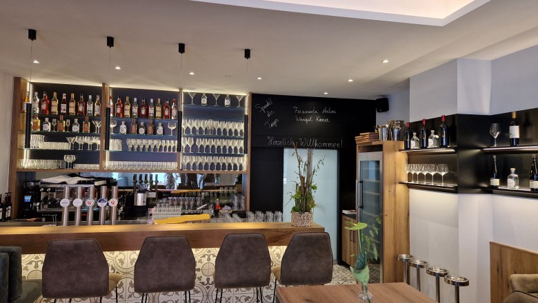 Modern bar with bottle racks, glasses and bar stools.