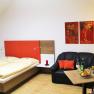 Gemütliches Zimmer mit Doppelbett, Sofa, Tisch und Stehlampe.